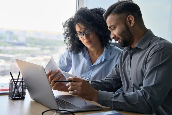 Man and woman sitting at a desk with a laptop and reviewing their MSP proposal.